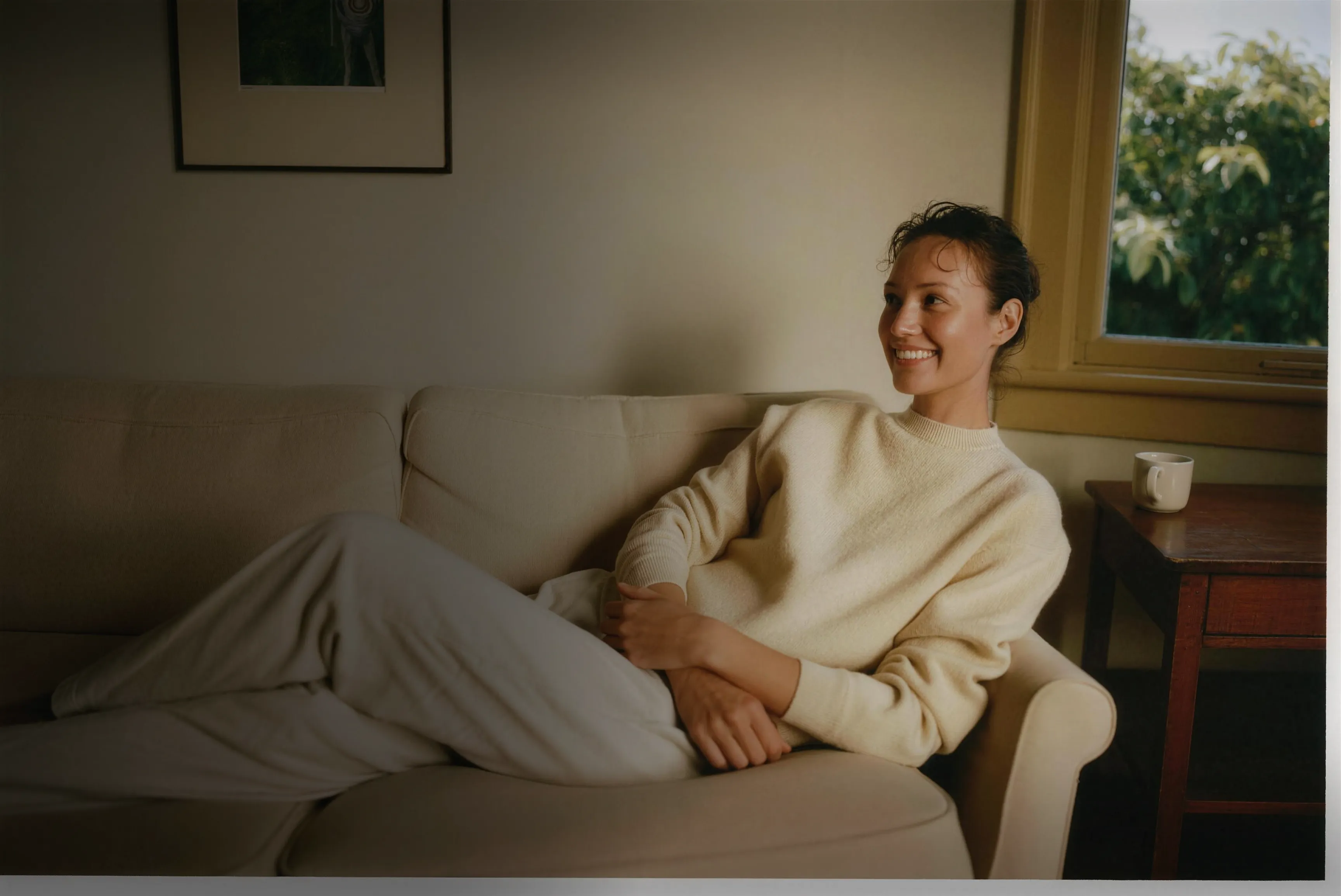 A woman smiling, relaxed at home in warm daylight