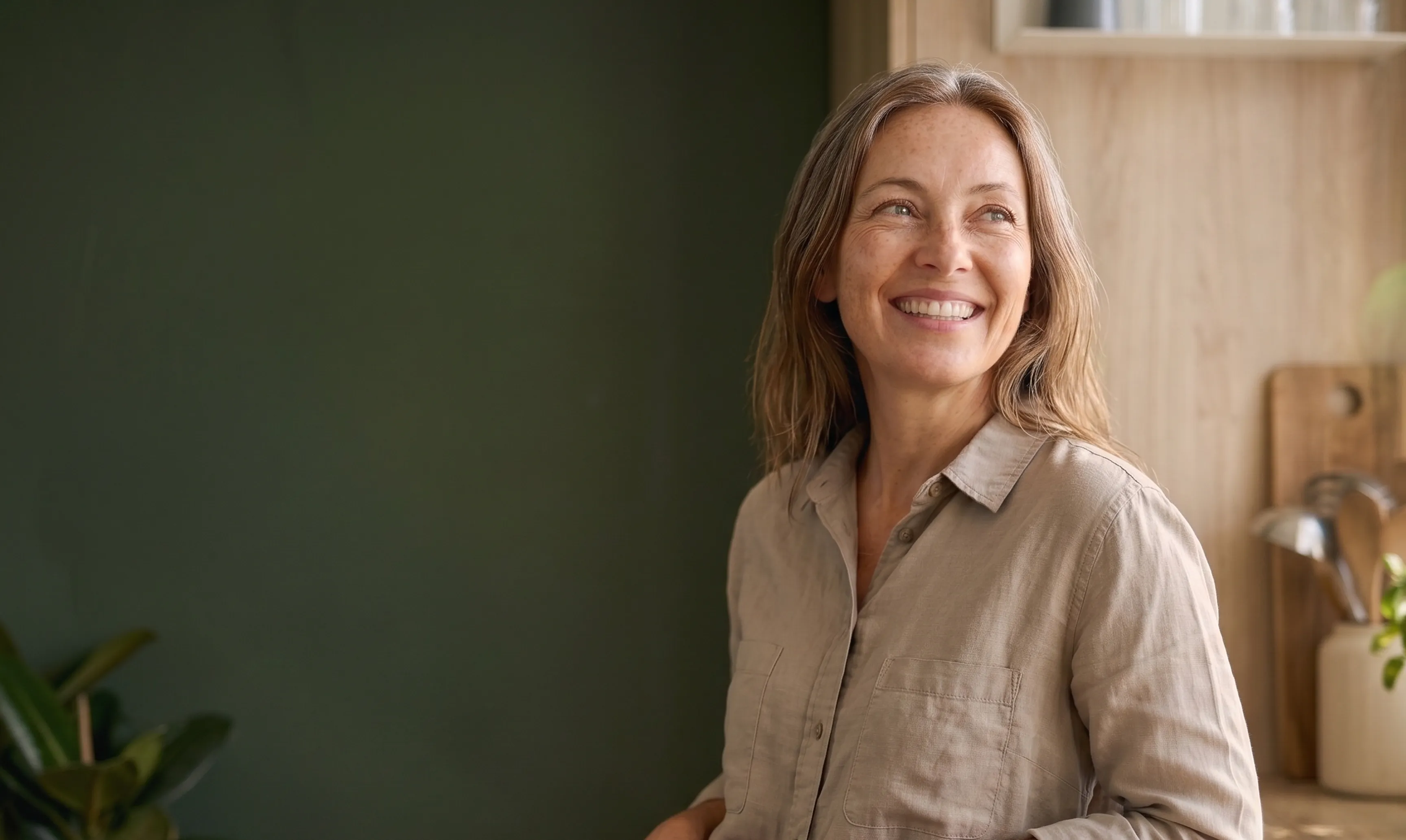 A woman smiling while holding a warm mug in soft natural light